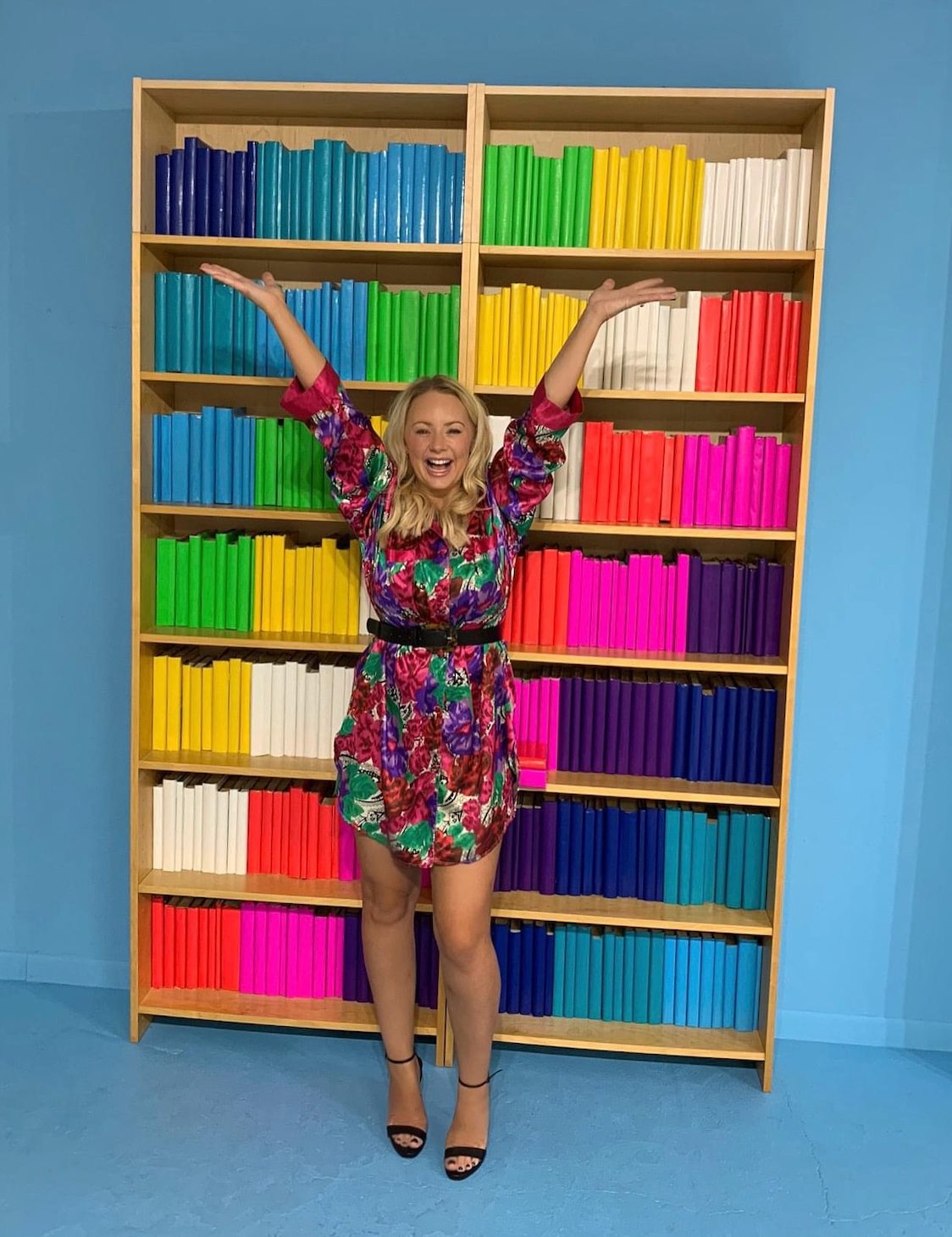 Rebecca laughing in front of colourful bookshelves